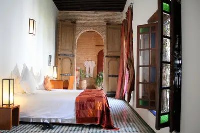 a bedroom with a bed in a room with a window at Riad Laaroussa in Fès