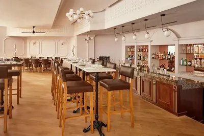 a restaurant with a long bar with stools at Fes Marriott Hotel Jnan Palace in Fès