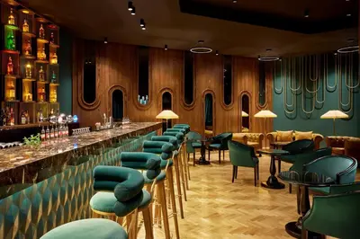 a bar with green chairs and a row of tables at Fes Marriott Hotel Jnan Palace in Fès