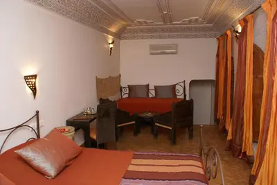 a bedroom with a bed and a table and a couch at Riad Attarine in Fès