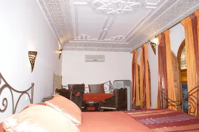 a bedroom with a bed with an ornate ceiling at Riad Attarine in Fès