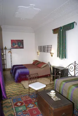 a room with two beds and a cross on the wall at Riad Attarine in Fès