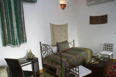 a bedroom with a bed and a table and a chair at Riad Attarine in Fès