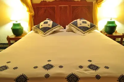 a bed with two pillows on it with two lamps at Riad Sara in Fès