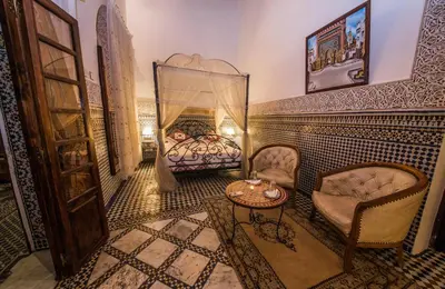 a room with a bed and a table and chairs at Riad Sara in Fès