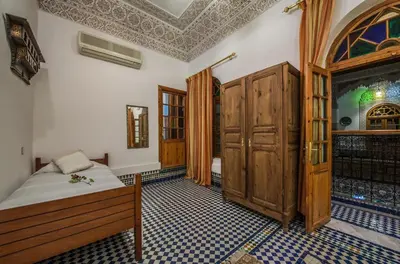 a bedroom with a bed and a wooden cabinet at Riad Sara in Fès