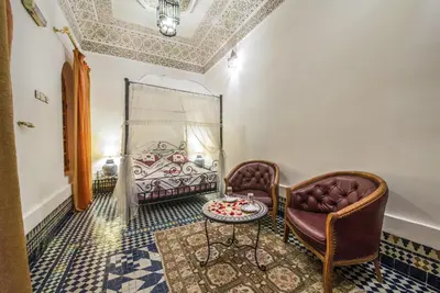 a bedroom with a bed and two chairs and a table at Riad Sara in Fès