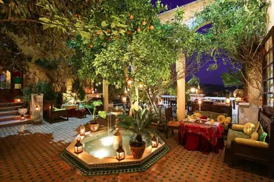 a restaurant with a hot tub with trees and tables at Riad Arabesque & Spa in Fès