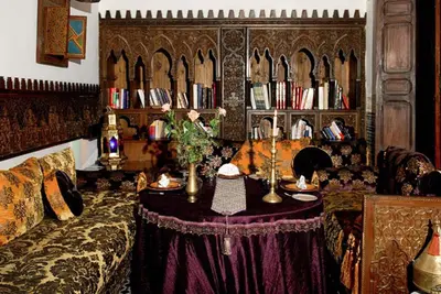 a living room with a couch and a book shelf with books at Riad Arabesque & Spa in Fès