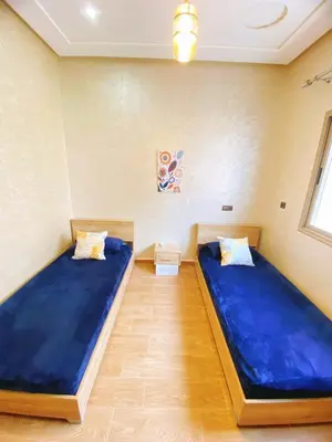 two beds in a room with blue sheets at Appartement calme à Fès in Fès