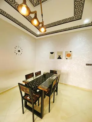 a dining room table with chairs and a clock on the wall at Appartement calme à Fès in Fès