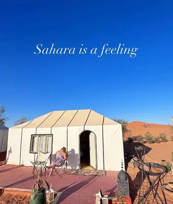 a woman sitting in a tent in the desert at Luxury Camp Merzouga & Activities in Merzouga