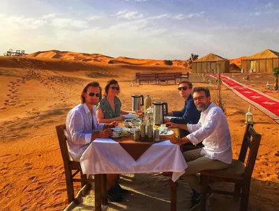 a group of people sitting at a table in the desert at Luxury Camp Merzouga & Activities in Merzouga