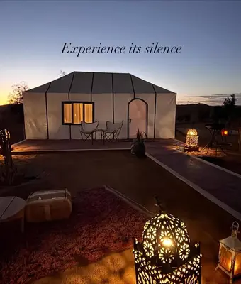 a large white tent with a table and chairs at Luxury Camp Merzouga & Activities in Merzouga