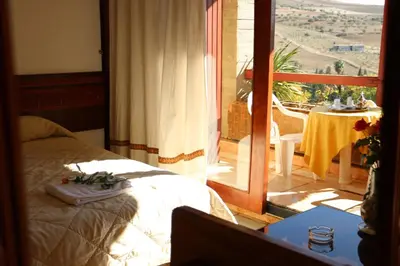 a bedroom with a bed and a balcony with a table at Sidi Harazem in Fès