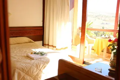 a bedroom with a bed and a balcony with a table at Sidi Harazem in Fès