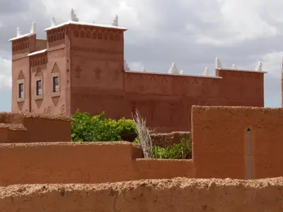 a building in the desert with a wall in the foreground at Gîte Assafar in Kalaat MGouna