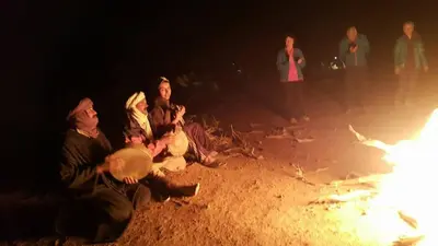 a group of people sitting next to a fire at Gîte Assafar in Kalaat MGouna