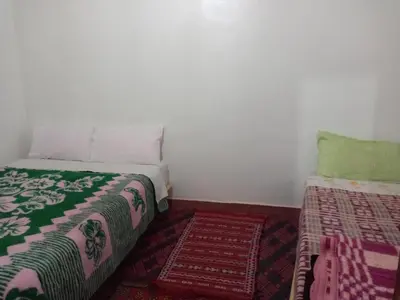 a small room with a bed and a pillow and a rug at Gîte Assafar in Kalaat MGouna