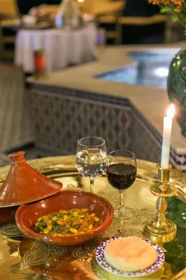 a table with a bowl of food and two glasses of wine at Riad Myra in Fès