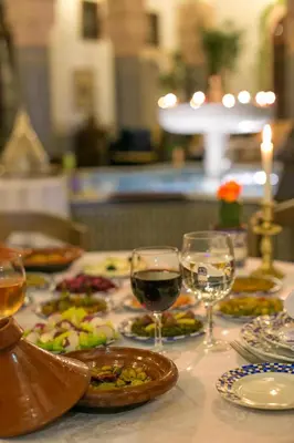 a table with plates of food and glasses of wine at Riad Myra in Fès