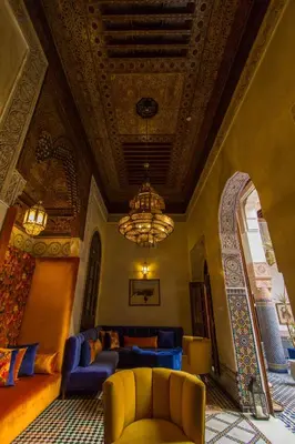 a living room with blue furniture and a chandelier at Riad Myra in Fès