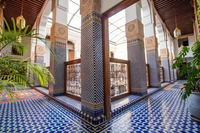 a lobby with a tile floor and a building with windows at Riad Myra in Fès
