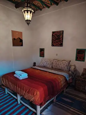 a bedroom with a large bed with a red blanket at DAR JOUD in Tabourahte