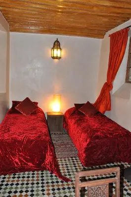 two red beds in a room with a lamp at Riad Au 20 Jasmins in Fès