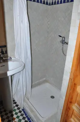 a shower with a white shower curtain next to a sink at Riad Au 20 Jasmins in Fès