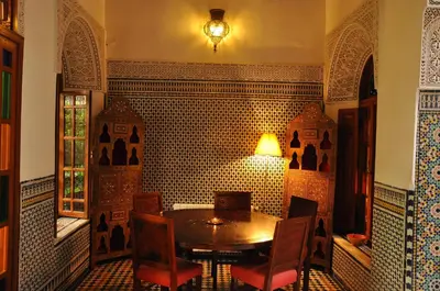 a table and chairs in a room with a tiled wall at Riad Au 20 Jasmins in Fès