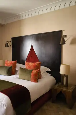 a bedroom with a large bed with a large headboard at Riad Fes - Relais & Châteaux in Fès