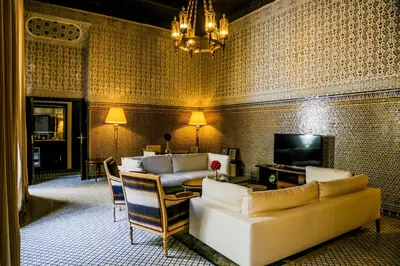 a living room with couches and a table and a television at Riad Fes - Relais & Châteaux in Fès
