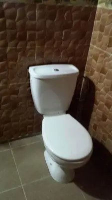 a white toilet in a bathroom with a brick wall at Guest House familly takojt in Merzouga