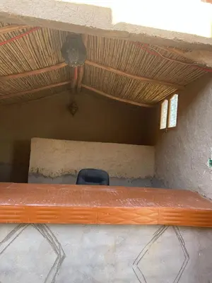 a bench in a room with a chair under a ceiling at Guest House familly takojt in Merzouga