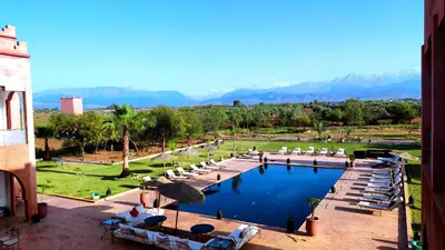 a swimming pool with lounge chairs and mountains in the background at Kasbah Caracalla in Aghmat