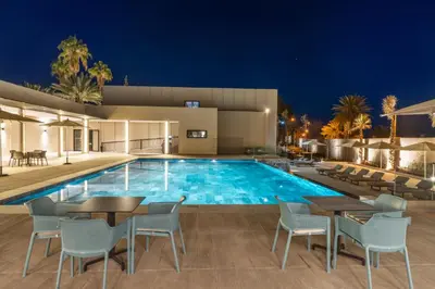 a pool with tables and chairs in front of a building at Kenzi Rissani in Er Rachidia