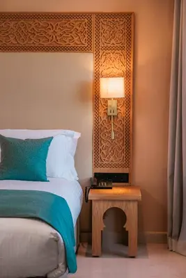 a bedroom with a bed and a table with a lamp at Kenzi Azghor in Ouarzazate