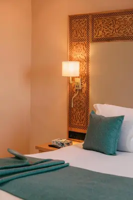 a bedroom with a bed and a lamp on a table at Kenzi Azghor in Ouarzazate