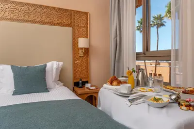 a hotel room with a bed with a tray of food on it at Kenzi Azghor in Ouarzazate