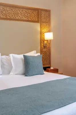 a bedroom with a large bed with a blue pillow at Kenzi Azghor in Ouarzazate