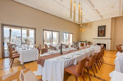 a large dining room with white tables and chairs at Kenzi Azghor in Ouarzazate