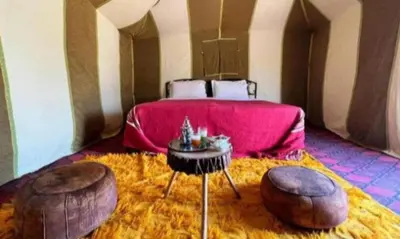 a bedroom with a bed with a table and two ottomans at Your journey starts here in Merzouga