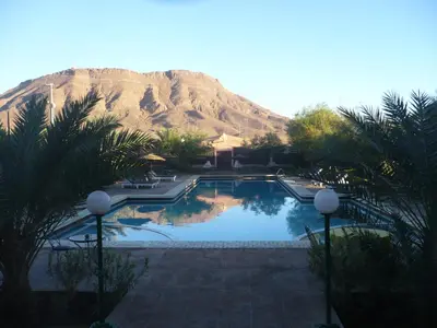 a large swimming pool with a mountain in the background at La Perle Du Drâa in Zagora