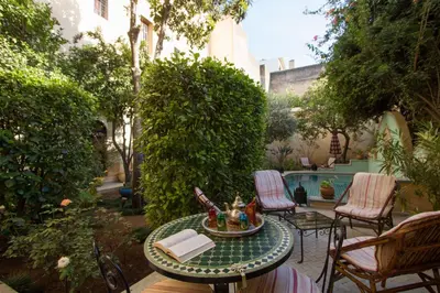 a patio with a table and chairs and a pool at Riad Norma in Fès