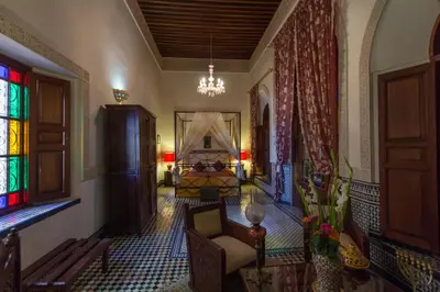 a living room with a chair and a chandelier at Riad Norma in Fès