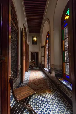 a hallway with a bench and stained glass windows at Riad Norma in Fès