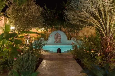 a person standing in front of a fountain in a garden at Riad Norma in Fès