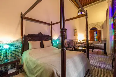 a bedroom with a canopy bed and a living room at Riad - Dar Al Andalous in Fès
