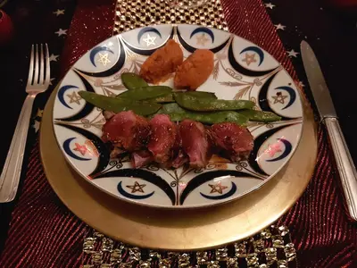 a plate with meat and green beans on a table at Riad Souafine in Fès